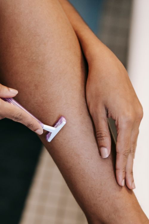Free Crop anonymous ethnic female depilating leg with plastic razor in bathroom at home in daytime Stock Photo