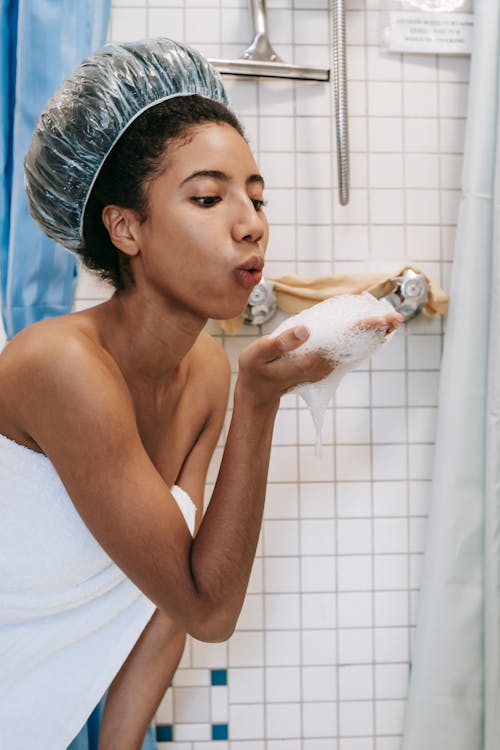 Free Ethnic female blowing foam in bathroom Stock Photo