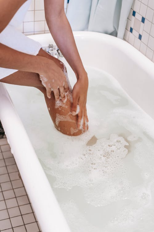 Этническая женщина моет ноги в ванне с пенной водой
