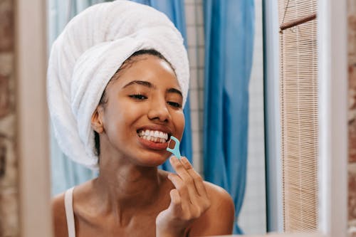 Ethnic woman cleaning teeth with dental floss