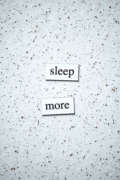 Free Motivational quote 'sleep more' on a minimalist speckled surface. Stock Photo