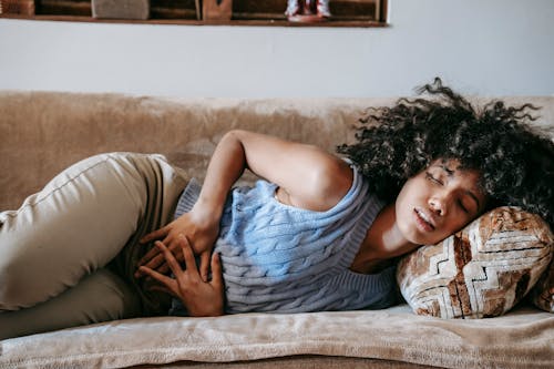 Wanita Menderita Sakit Perut Berbaring Di Sofa