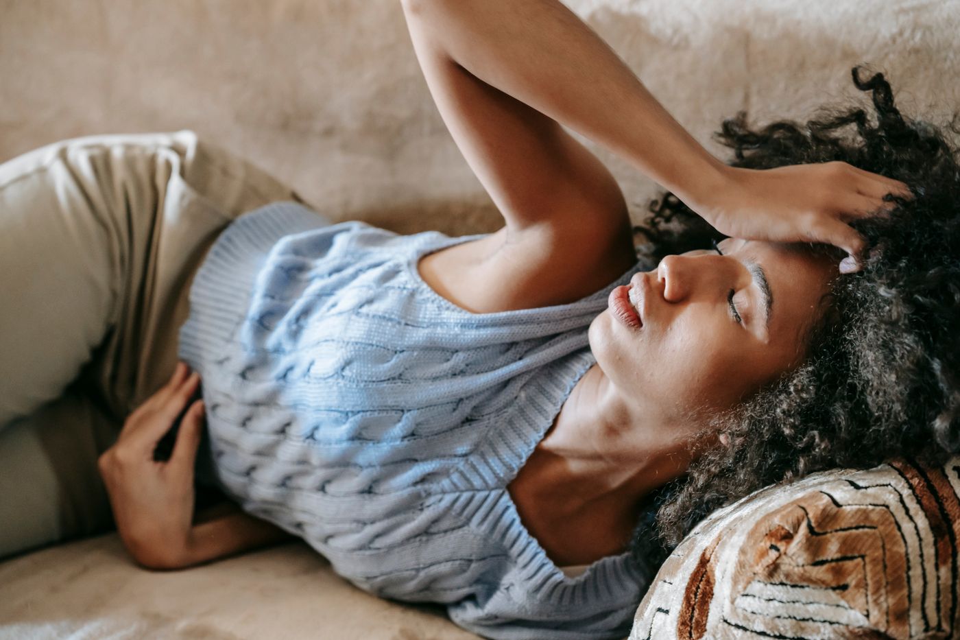 Young African American woman resting on a sofa while experiencing a headache