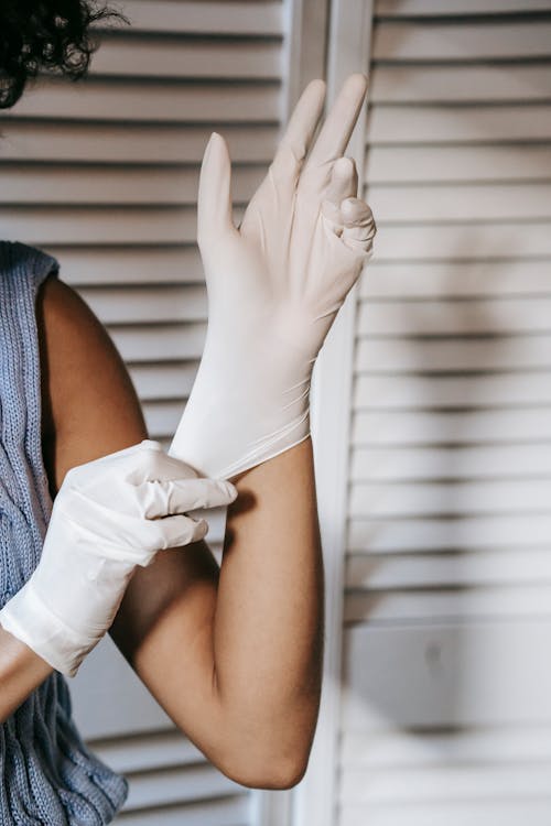 Faceless woman putting on medical gloves