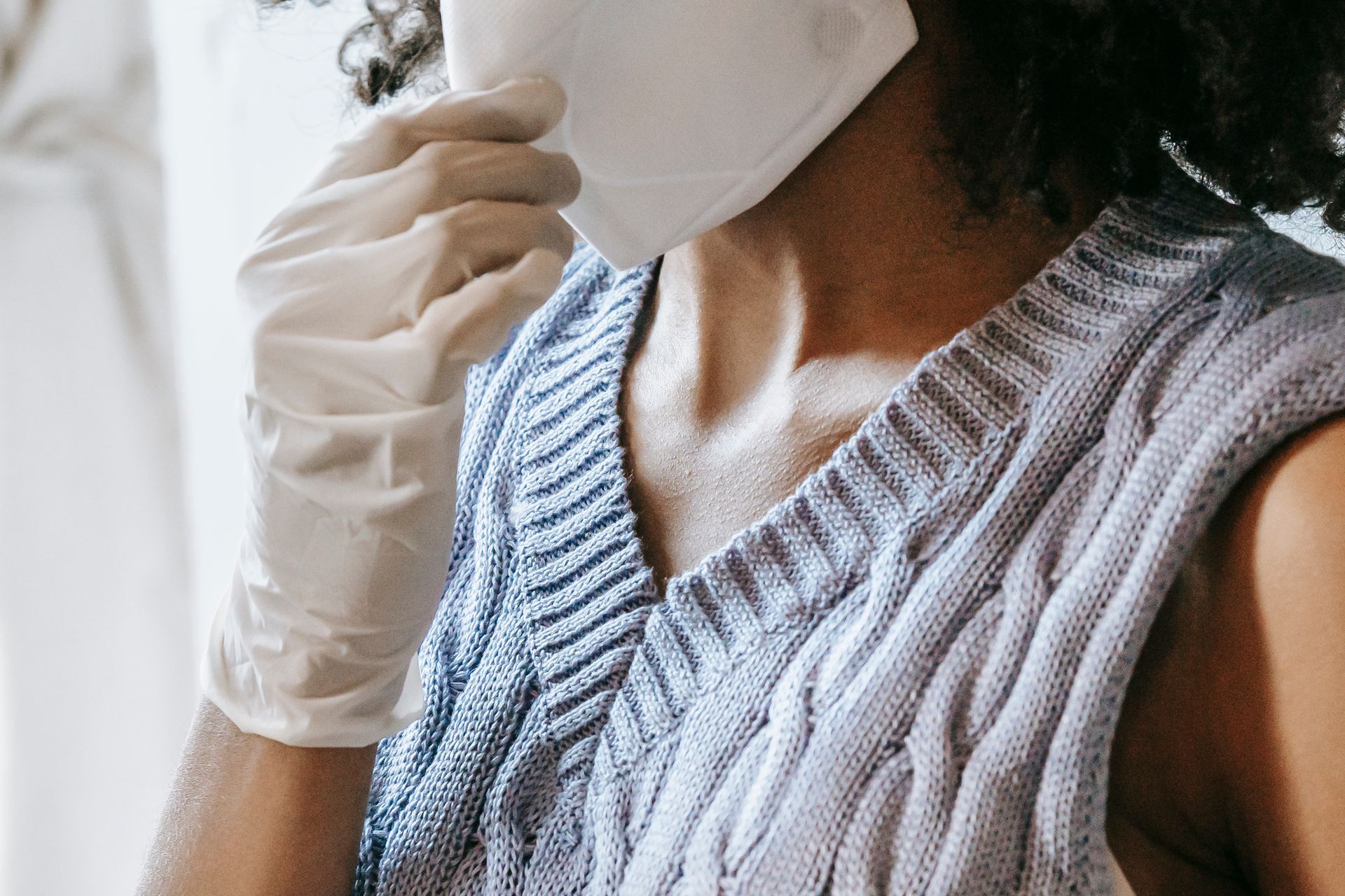 Close-up of a woman wearing a protective mask and gloves indoors, highlighting safety precautions.