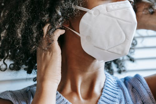 Black woman putting on protective mask