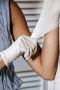 Crop faceless female in sleeveless sweater wearing white medical rubber gloves to protect hands