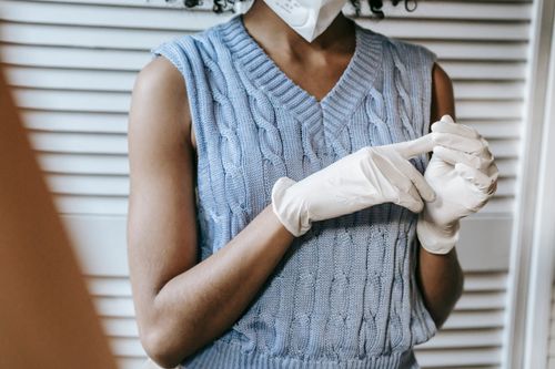 Free Crop anonymous African American female in casual outfit and wearing white protective face mask and medical rubber gloves Stock Photo