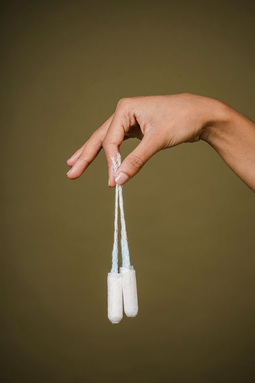 Free Crop anonymous female demonstrating tampons for menstruation on olive background of studio Stock Photo