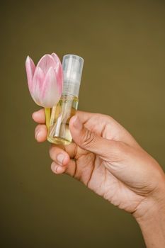 一名匿名女性在工作室的橄榄色背景下展示手中的郁金香和香水