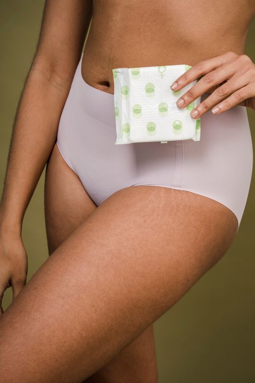 Free Crop anonymous female with package of sanitary pad for menstrual period on olive background Stock Photo