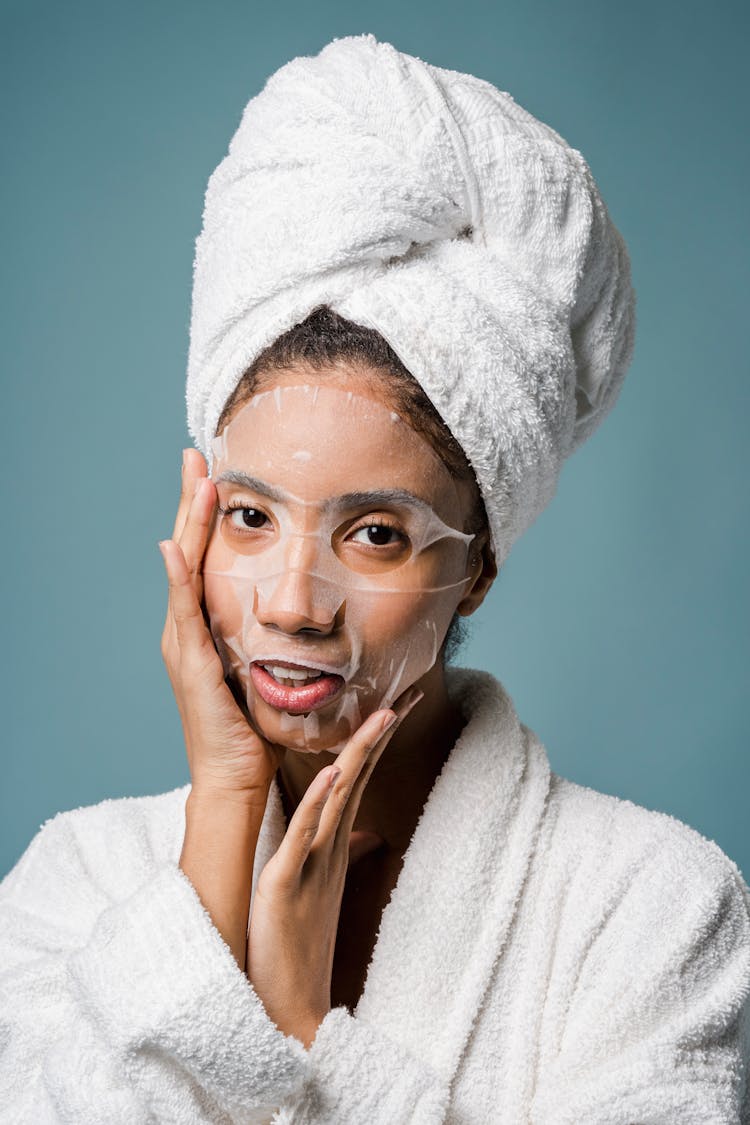 Ethnic Female In Towel On Head Applying Face Mask