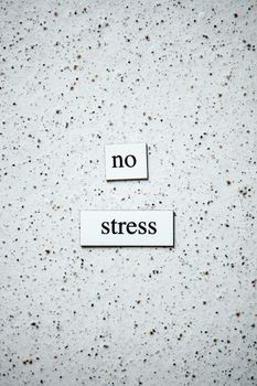 Minimalist text displaying 'no stress' on a textured speckled surface, promoting calmness.