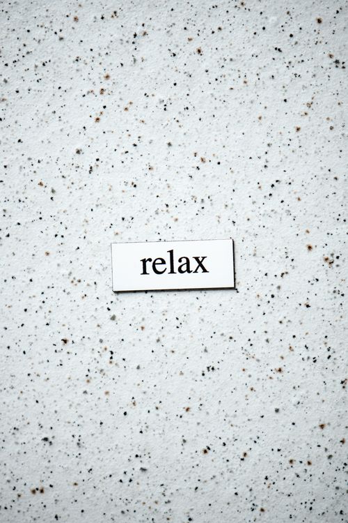 Free Simple minimalist typography reading 'relax' on a speckled surface with ample copy space. Stock Photo