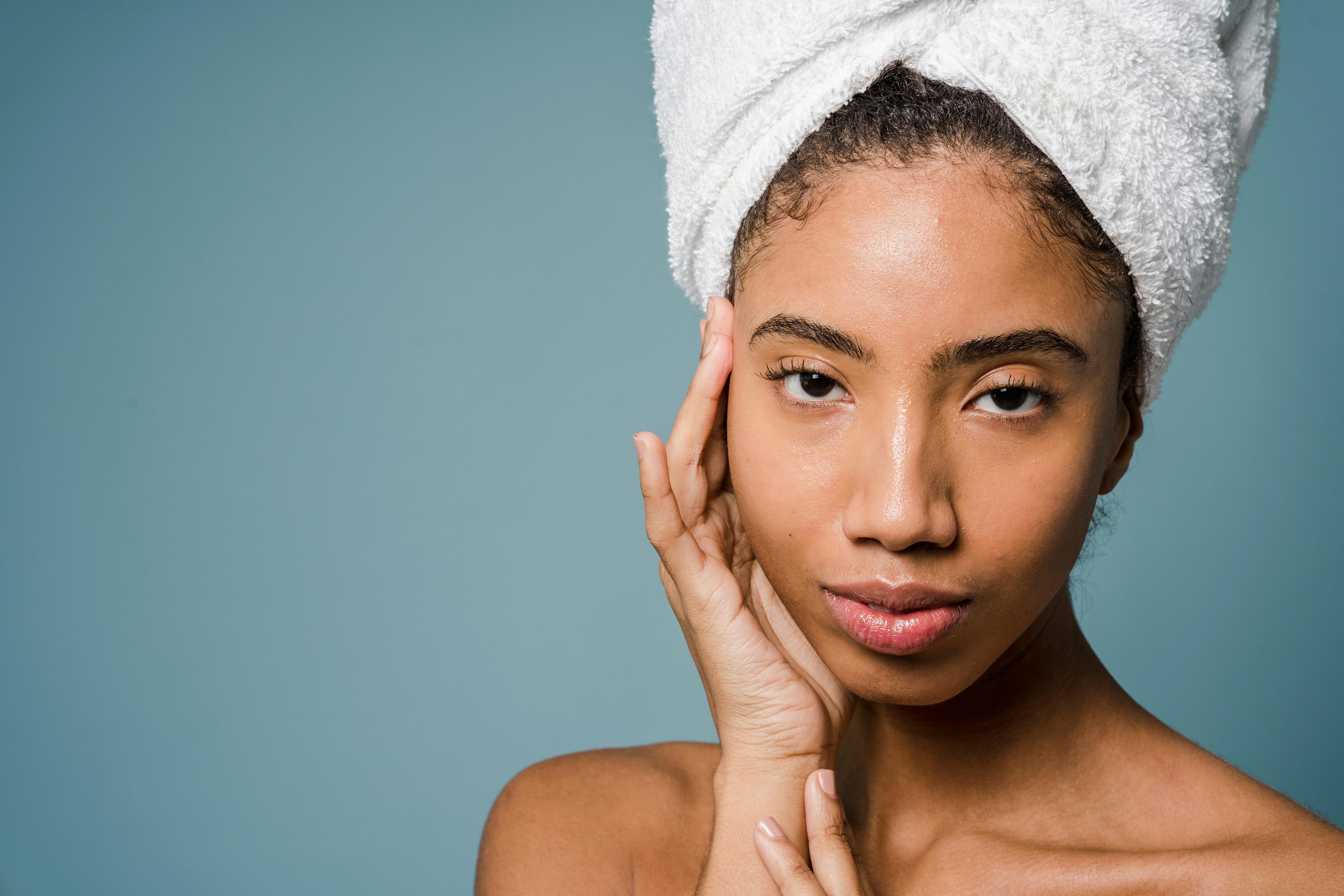 black woman in white towel turban touching face and looking at camera