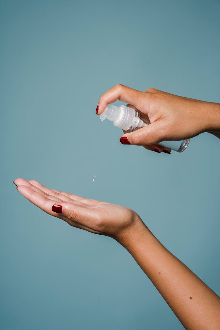 Female Showing Bottle Of Lotion Against Blue Background