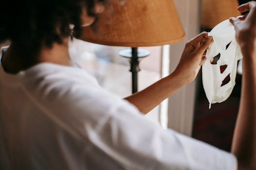 A woman holds a skincare sheet mask in a cozy home setting, emphasizing beauty and self-care routines.