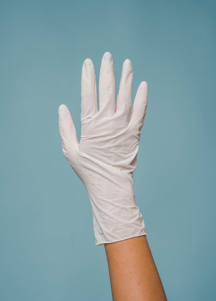 Hand In Medical Glove Against Blue Background