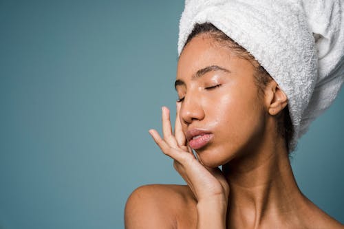 African American lady touching face after shower against blue background