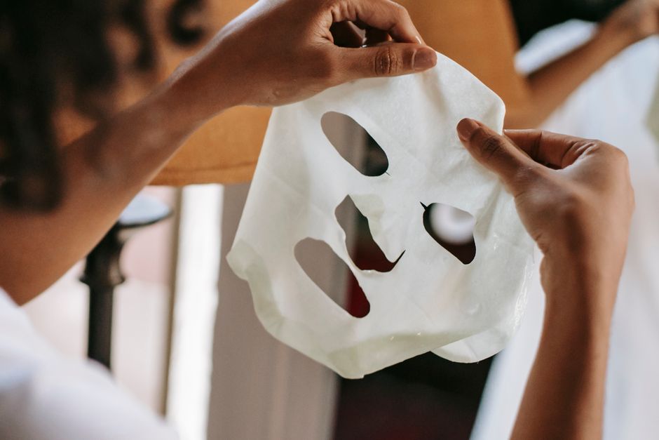 Crop anonymous African American woman with dark curly hair standing in front of mirror and holding sheet mask at home in daytime — Photo by Sora Shimazaki on Pexels