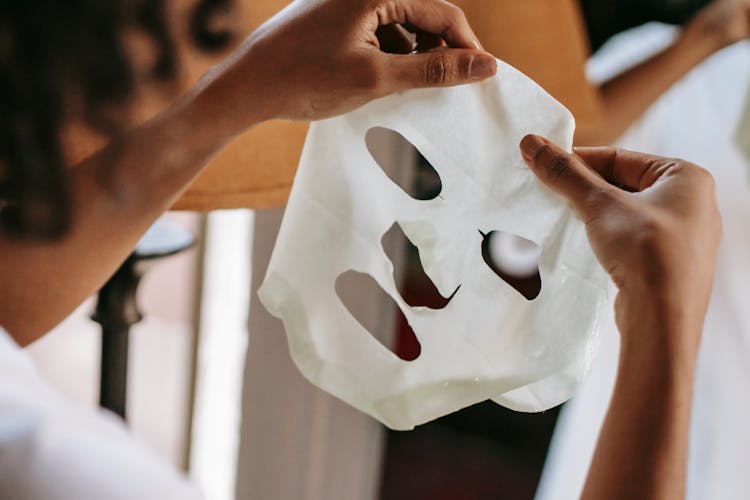 Ethnic Female Holding Sheet Mask At Home