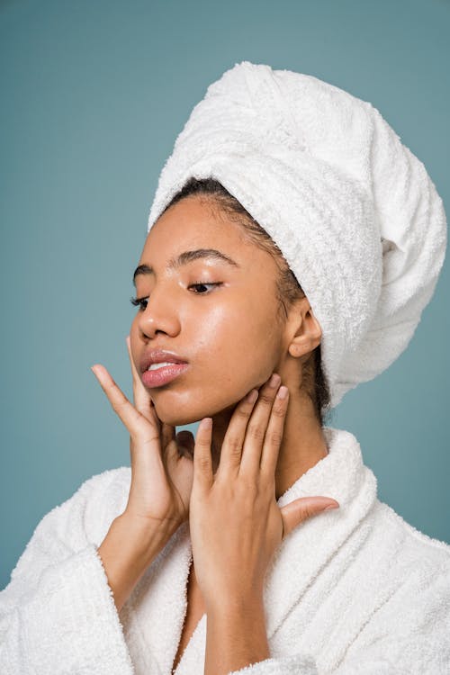 Free Calm African American female in bathrobe touching face against blue background Stock Photo