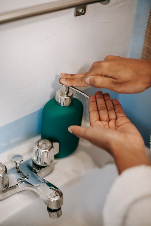 Person using faucet with soap in bathroom