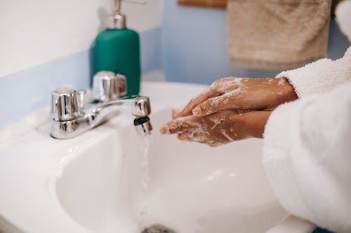 Free Black woman washing hands in bathroom Stock Photo