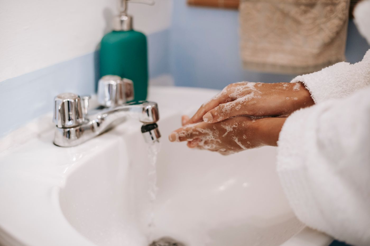 Black woman washing her hands thoroughly with soap under running water