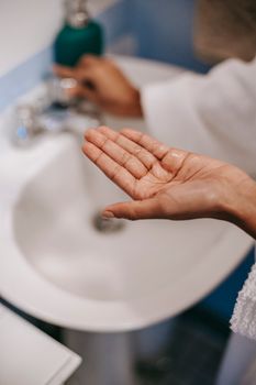 A close-up of a hand over a sink, ready for a skincare routine. Indoors, clean and fresh feel.