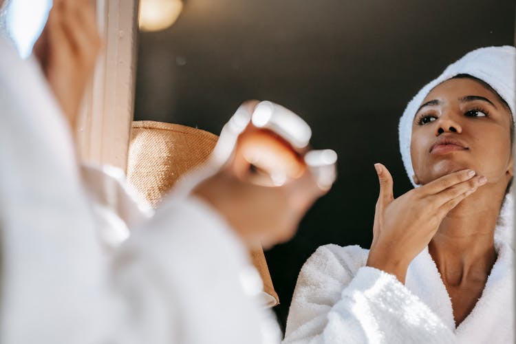 Black Woman Applying Cream On Face