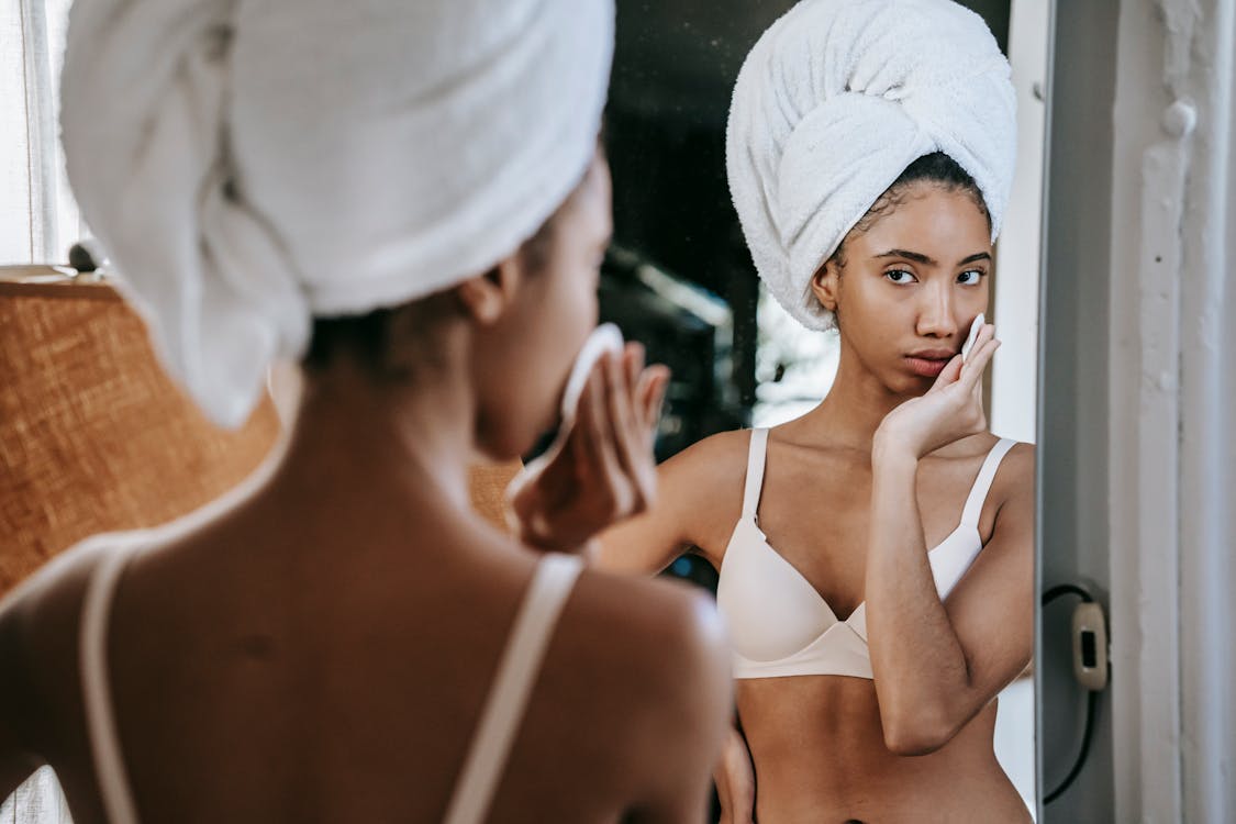 Ethnic woman wiping face skin with cotton pad