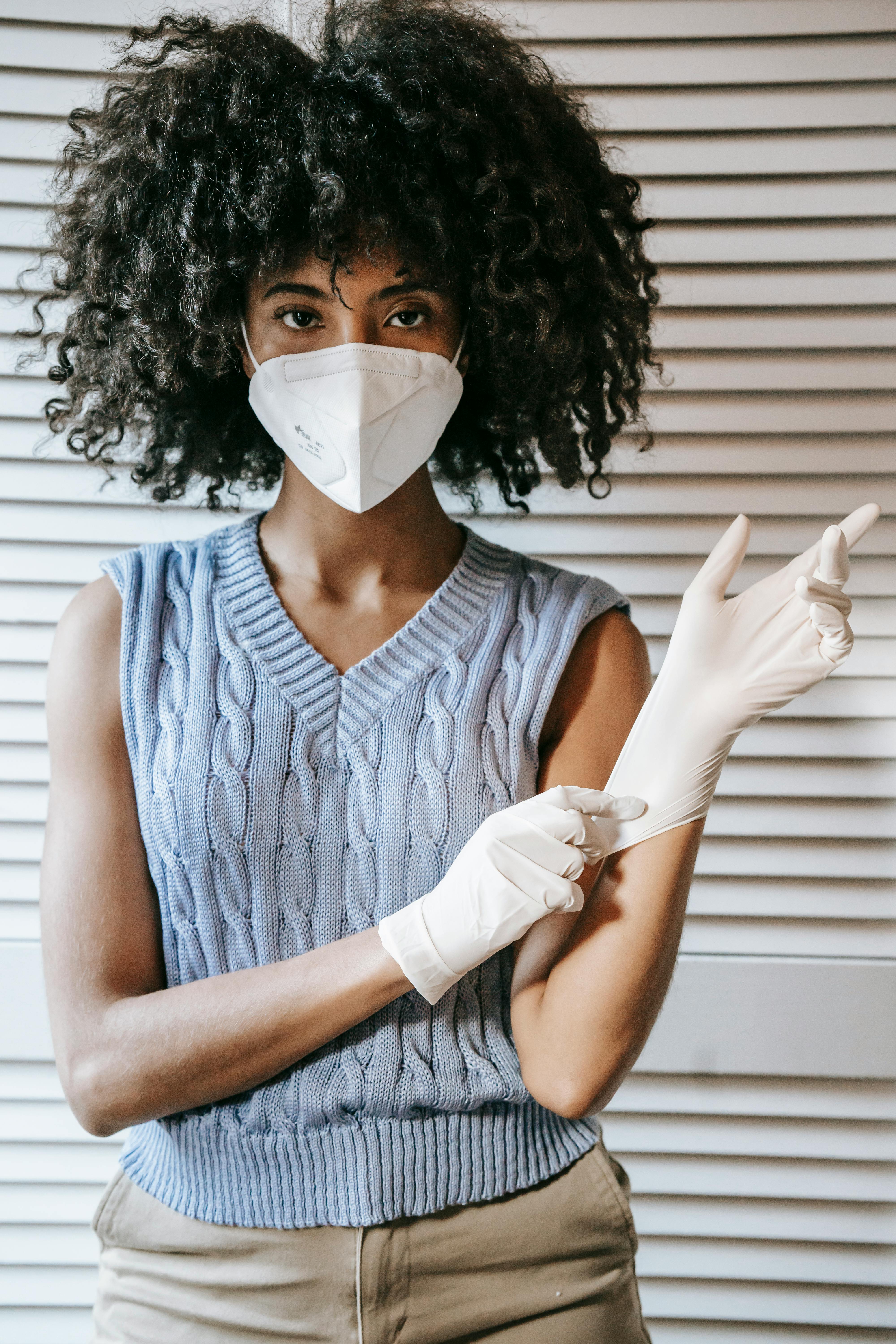 ethnic woman putting on gloves during coronavirus pandemic