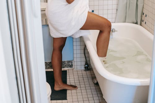 Free Ethnic woman putting leg in bath in morning Stock Photo