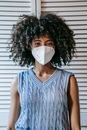 Ethnic woman in protective mask against white shutters