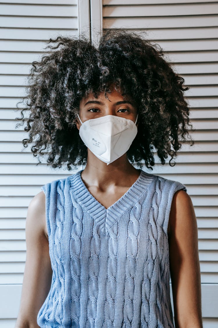 Ethnic Woman In Protective Mask Against White Shutters