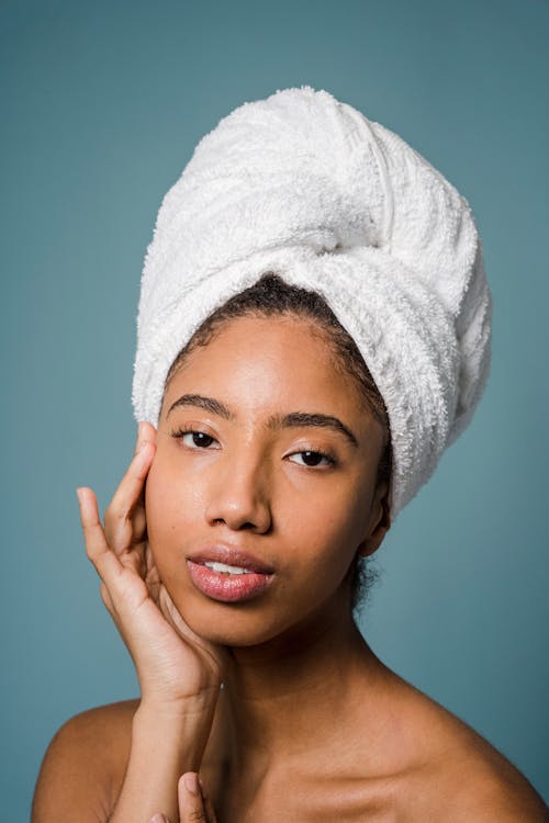 Alluring young black female touching face and looking at camera after shower