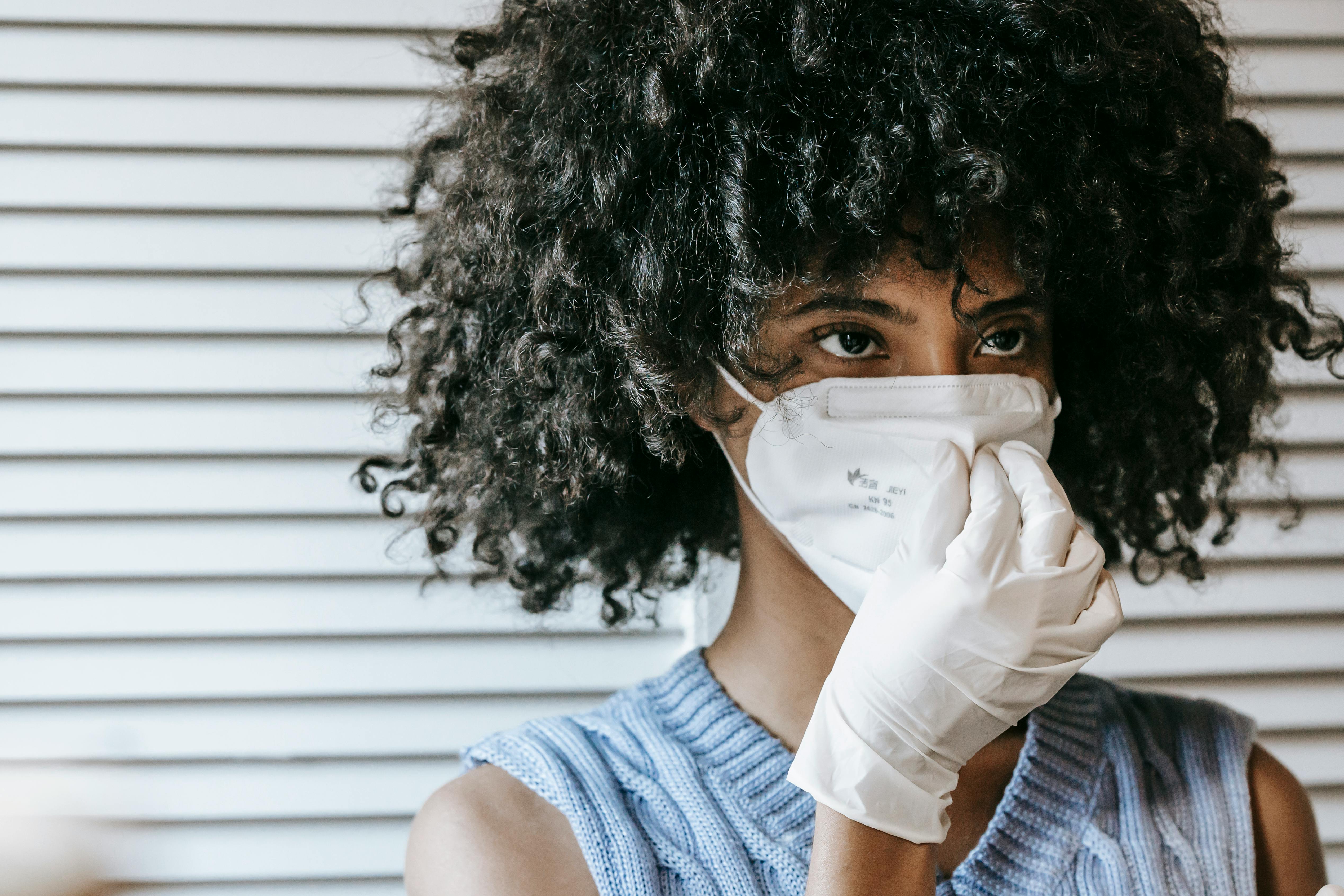 anonymous concentrated black lady in mask and gloves during covid