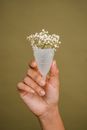 Faceless woman showing menstrual cup with tender white flowers