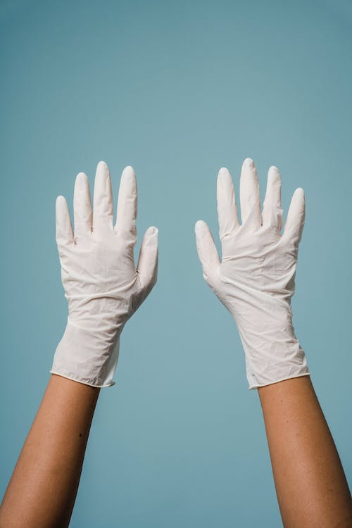 Anonymous woman hands in protective gloves in blue studio