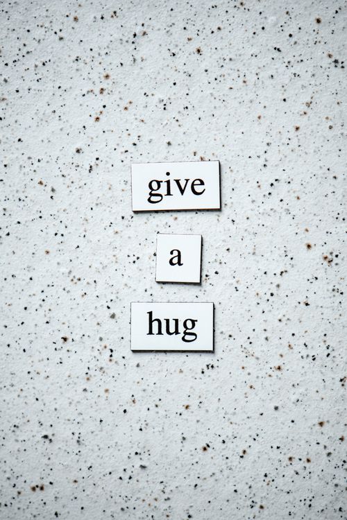 Free Motivational message 'Give a Hug' on a speckled surface for encouragement and support. Stock Photo