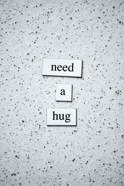 Free Simple text art displaying the phrase 'need a hug' against a speckled surface, using western script. Stock Photo