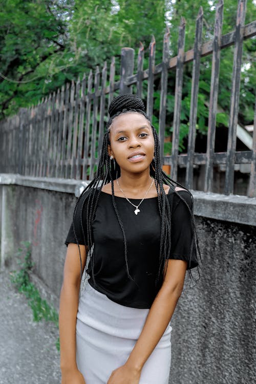 Woman with Braided Hair Standing Beside Concrete Fence