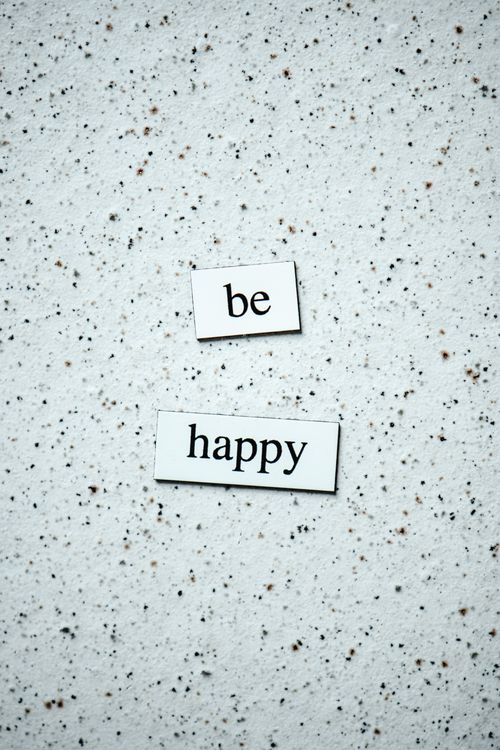 Free Inspirational quote 'Be Happy' on a textured marble background, perfect for motivation. Stock Photo