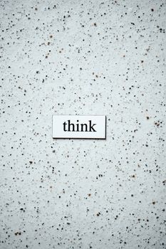 Minimalist photo featuring the word 'think' on a textured background, inspiring contemplation.