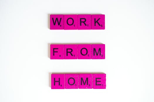 Pink Scrabble tiles spelling 'Work From Home' on a white background, conveying remote work theme.