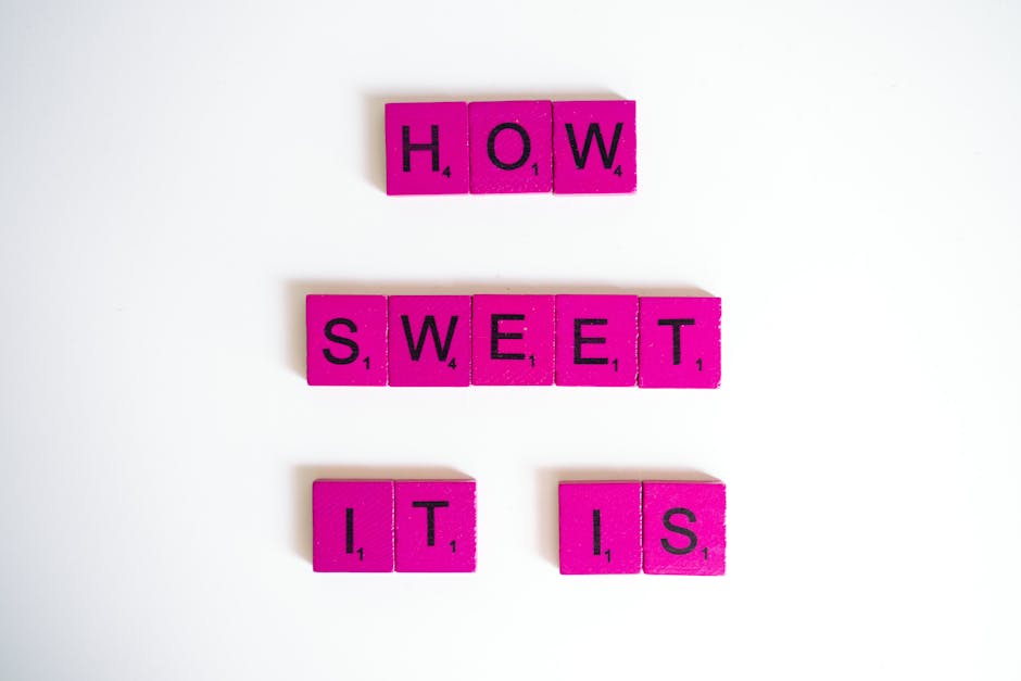 Bright pink Scrabble tiles spelling 'How Sweet It Is' on a white surface.