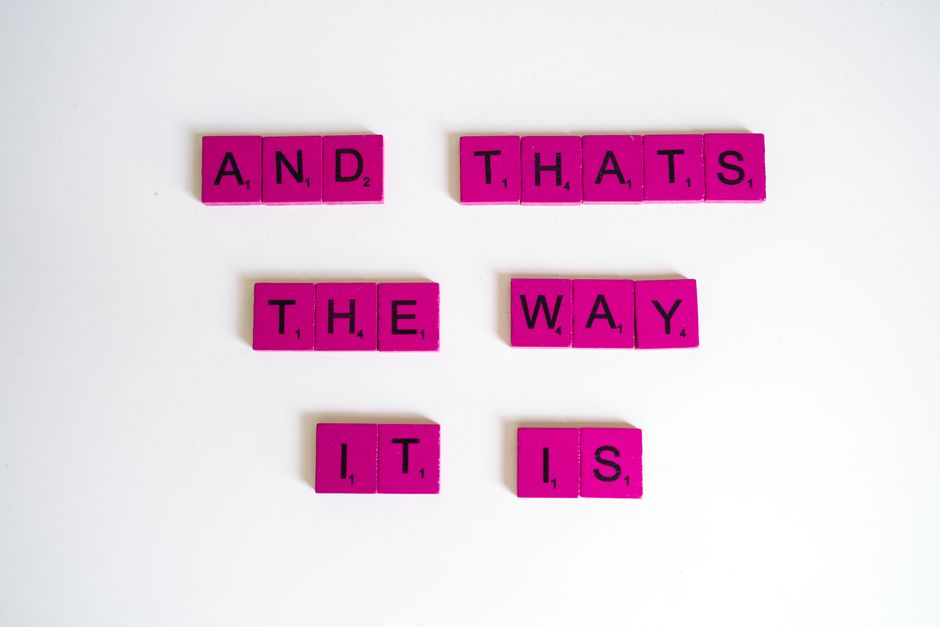 Inspirational quote 'And That's The Way It Is' on pink Scrabble tiles.