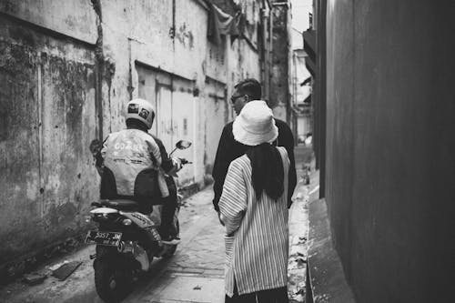 Grayscale Photo of People Passing by the Sidewalk