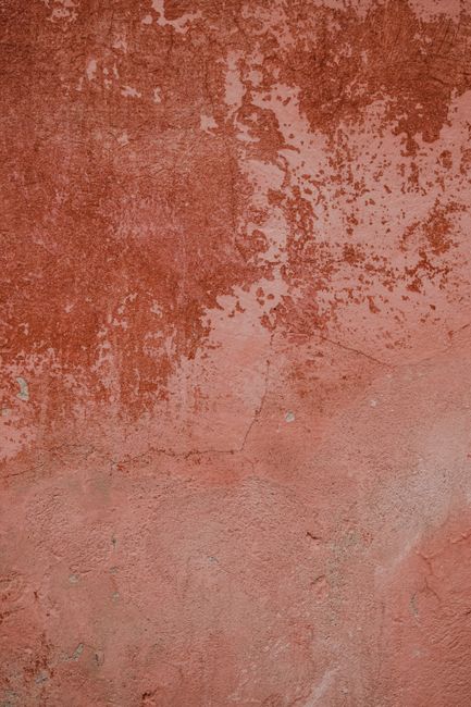 Close-up of a red plaster wall showcasing natural texture and weathered patina.